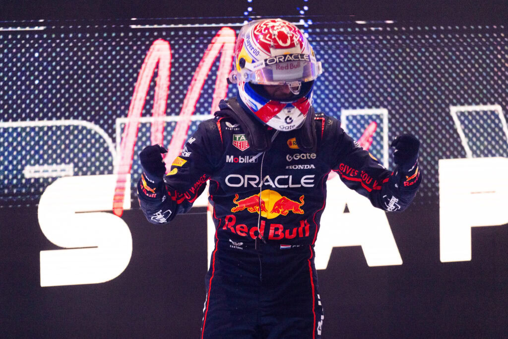MotoGP racer celebrating on the podium with Red Bull Racing Honda sponsorship logos visible.