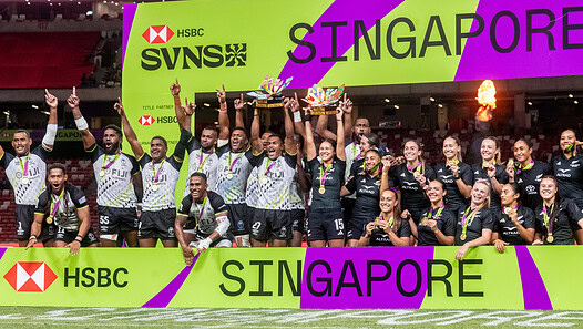 Victorious women's rugby team celebrating win at Singapore HSBC Women's Sevens tournament.