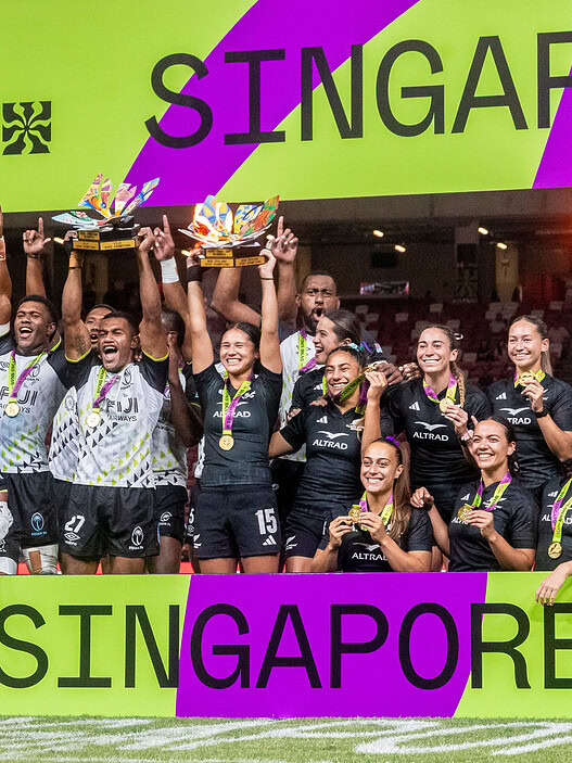 Victorious women's rugby team celebrating win at Singapore HSBC Women's Sevens tournament.