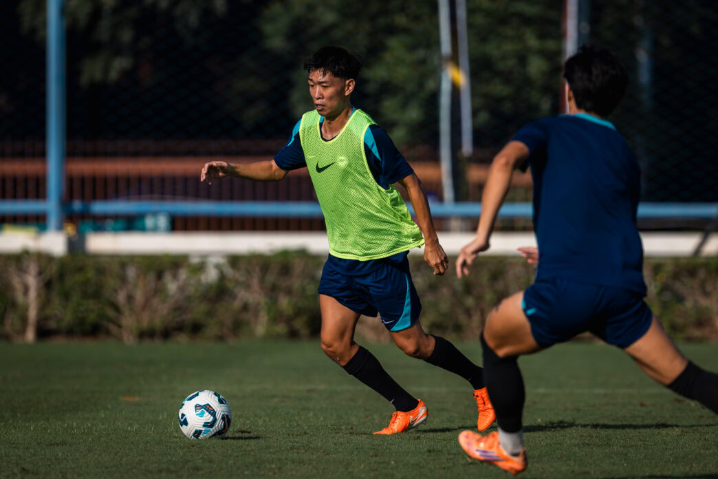 Youth soccer players in action on a sunny outdoor field in Singapore.