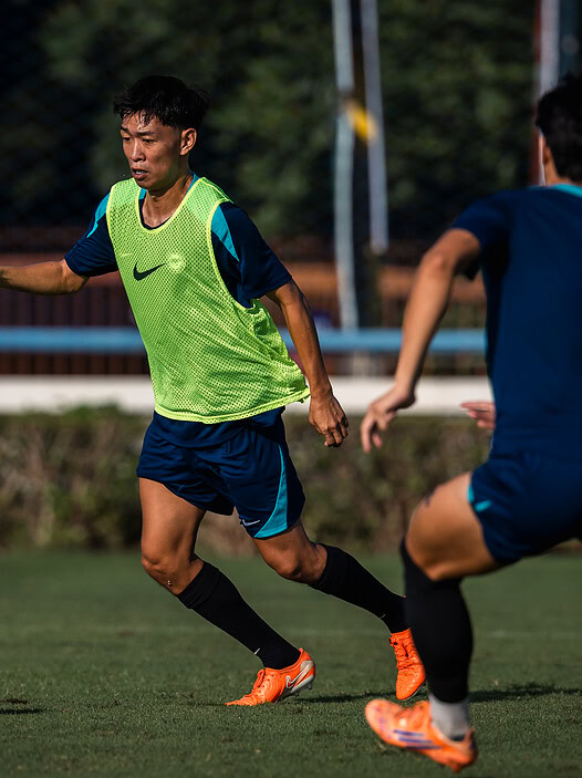 Youth soccer players in action on a sunny outdoor field in Singapore.