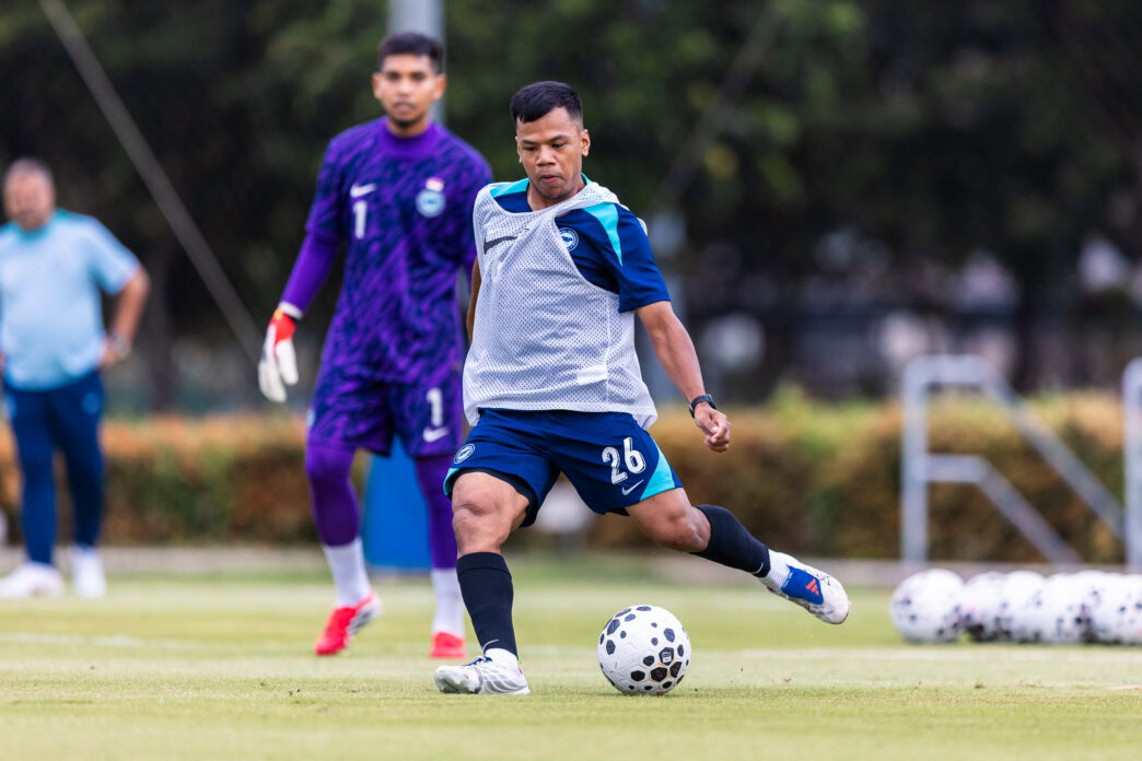 Young soccer player practicing dribbling on the field during training session.