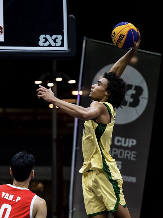 Female basketball player in yellow uniform making a slam dunk during a 3x3 basketball game.