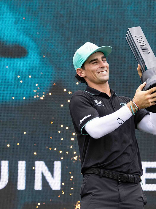 Golfer holding trophy at a golf tournament celebration in Singapore.